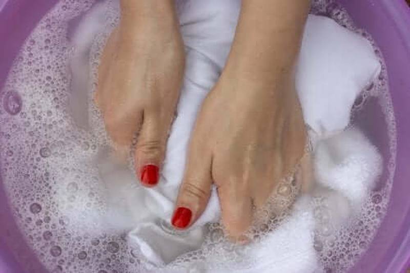 Mão de mulher lavando roupa branca