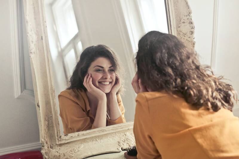 Mulher sorrindo no espelho