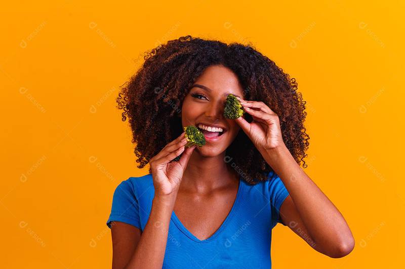 Foto de mulher negra comendo brócolis