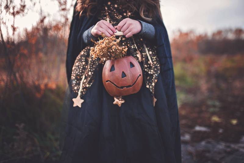 Mulher disfarçada de bruxa segura abóbora, em clara referência ao Halloween (Dia das Bruxas)