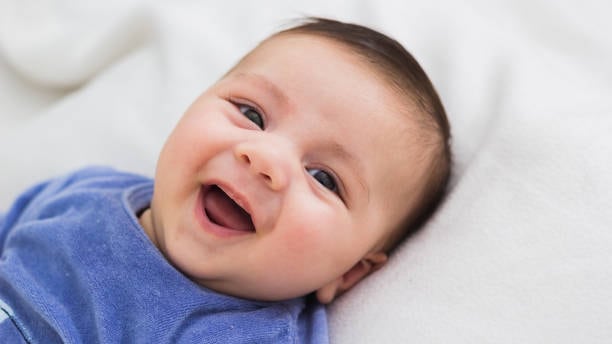 close up of smiling baby lying in his crib